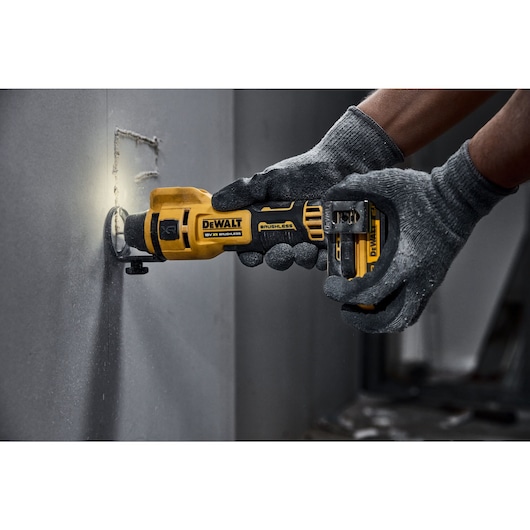 A tradesman using a DCE555 to cut a hole in drywall