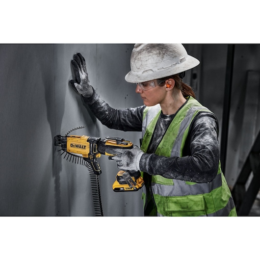 individual using a 20V MAX XR(®) Brushless Drywall Screwgun with collated attachment on a wall