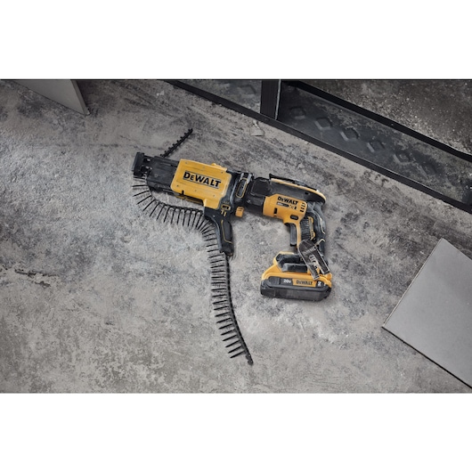 Drywall screwgun with collated attachment on floor and cutout tool on floor in commercial setting
