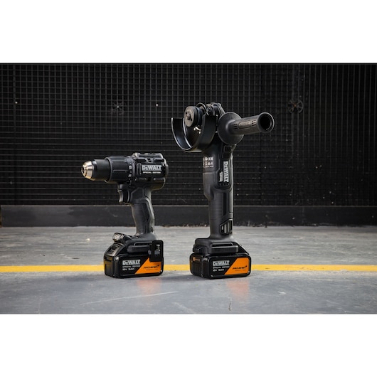 DEWALT x McLaren F1 Team 18V XR Special Edition Hammer Drill Driver and Grinder with 5Ah batteries standing on a concrete floor
