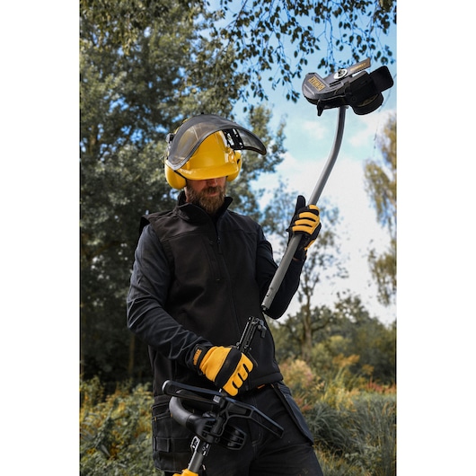 Worker attaching the DEWALT DCMASED9N Edger Attachment to a DEWALT split boom