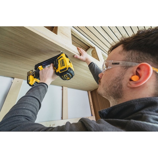 DEWALT tools (BSV520BRB, DCN210SN-XJ) used for woodwork. Person with ear plugs handles them. Photography category.