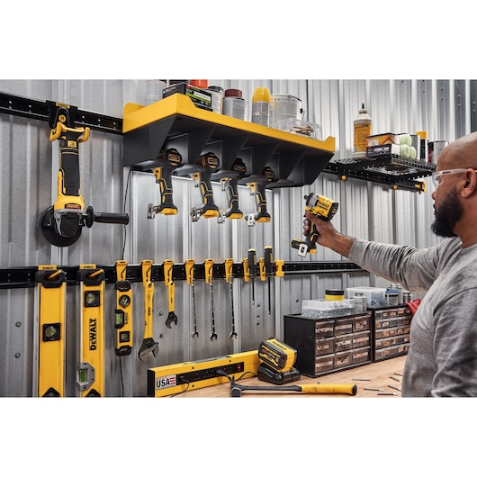 A Person Grabbing a DEWALT Power Tool Out of a DEWALT Power Tool Holster Featuring  Metal Rails, Hand Tools and Accessories.